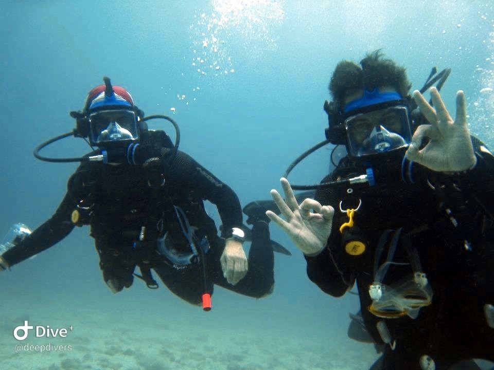Dos buzos bajo el agua saludando